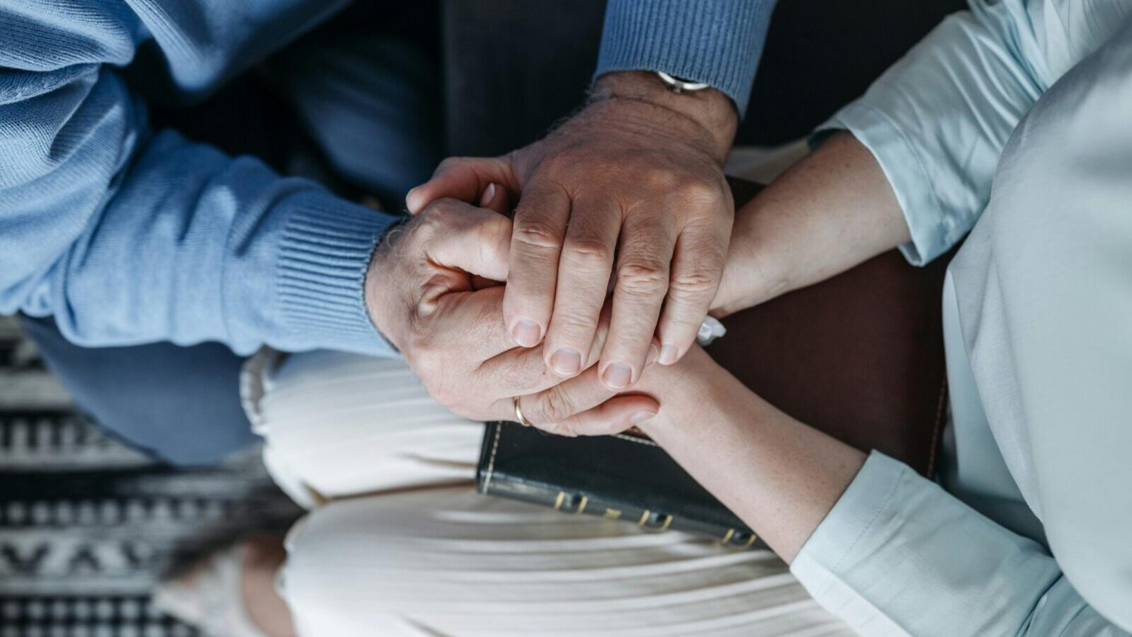 Close-up of two people holding hands, expressing comfort and empathy.